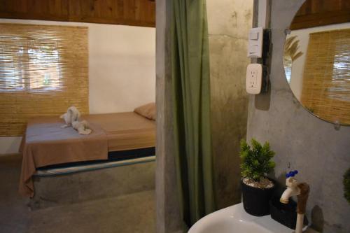 a bathroom with a bed and a sink and a mirror at Hotel El Delfin in Monterrico