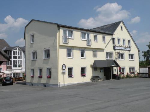 un grand bâtiment blanc situé dans un parking dans l'établissement Landgasthof Grüne Linde, à Hof