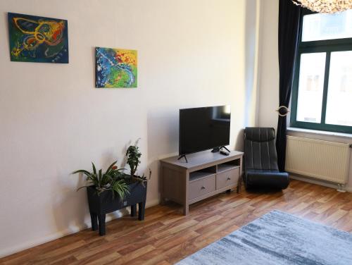 ein Wohnzimmer mit einem Flachbild-TV und einem Stuhl in der Unterkunft Ferienwohnungen in der Kunstgalerie Charlie und Jenny in Chemnitz