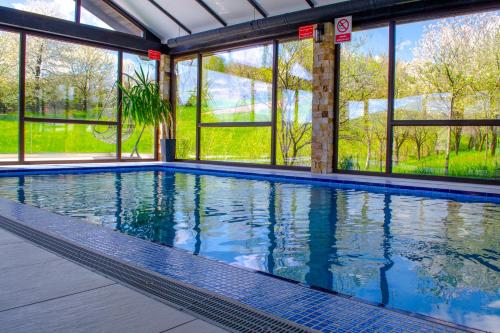 a swimming pool in a building with windows at Bucovina Residence & SPA in Gura Humorului