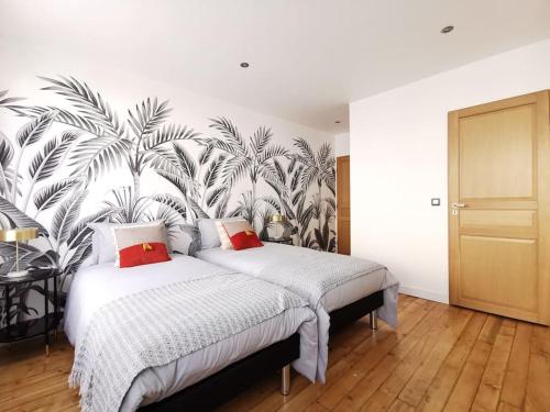 een slaapkamer met 2 bedden en een muurschildering van palmbomen bij Les bulles d'Ay - Terrasse in Ay