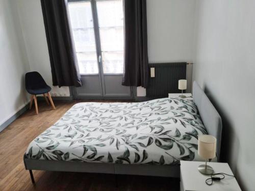 Schlafzimmer mit einem Bett mit einer schwarzen und weißen Bettdecke in der Unterkunft Appartement de 3 chambres avec wifi a Beaugency in Beaugency