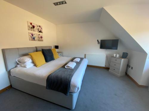 ein Schlafzimmer mit einem Bett mit gelben Kissen und einem TV in der Unterkunft Highland Stays - Ben View Double Rooms in Fort William