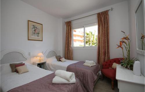 カサーレスにあるAmazing Apartment In Casares With House A Mountain Viewのベッド2台、椅子、窓が備わる客室です。