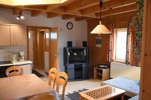a living room with a tv and a table and a kitchen at Ferienhaus Nr 13B1, Feriendorf Hagbügerl, Bayr Wald in Waldmünchen