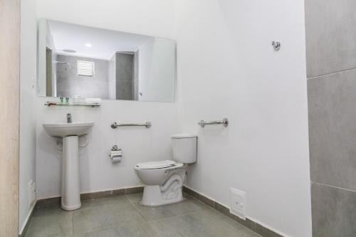 een badkamer met een toilet, een wastafel en een spiegel bij Hotel Palma Verde in Armenia