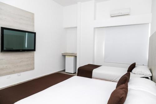 a hotel room with two beds and a tv at Hotel Palma Verde in Armenia