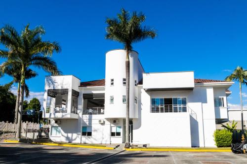 a white building with palm trees in front of it at Hotel Palma Verde in Armenia