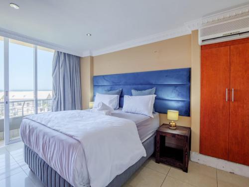 a bedroom with a large bed with a blue headboard at The Sails Apartment 2 Bed 2 Bath Seaview Apartment - C5 in Durban