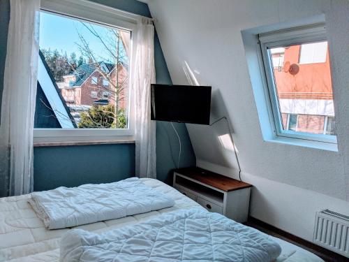 a bedroom with a bed and a window with a television at Dat lütte Strandhuus in Cuxhaven