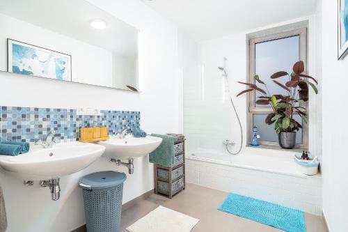 Baño blanco con 2 lavabos y bañera en House with private parking & sauna near city centre and transport, en Roeselare