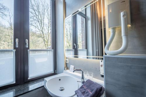 a bathroom with a sink and a toilet and a mirror at Hotel des Comtes Durbuy in Durbuy