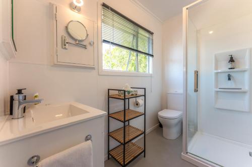Un baño con lavabo, inodoro y ventana. en Four Palms Cottage - Onetangi Holiday Home, en Onetangi