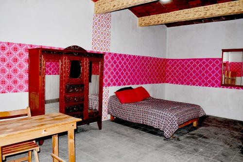 - une chambre avec un lit, une commode et des murs roses dans l'établissement Ojo de Luna Teotitlan, à Teotitlán del Valle
