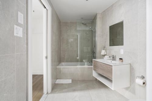 ein weißes Badezimmer mit einer Badewanne und einem Waschbecken in der Unterkunft Bakan- Palais des Congres, Convention Centre in Montreal