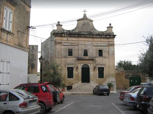 um edifício antigo com carros estacionados num parque de estacionamento em Townhouse Twenty em Żebbuġ