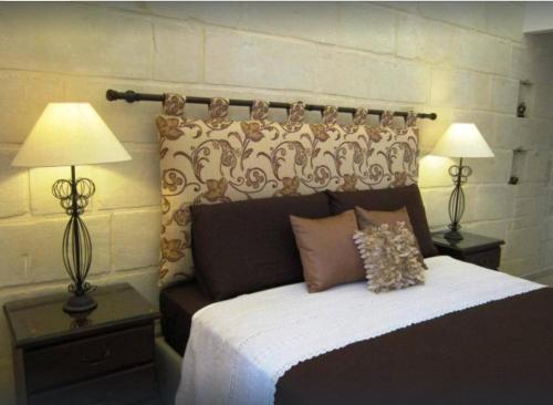 a bedroom with a large bed with two lamps at Townhouse Twenty in Żebbuġ