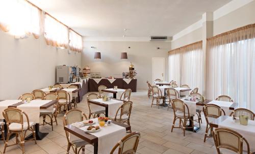 a dining room with white tables and chairs at Hotel Spinelli in Viareggio