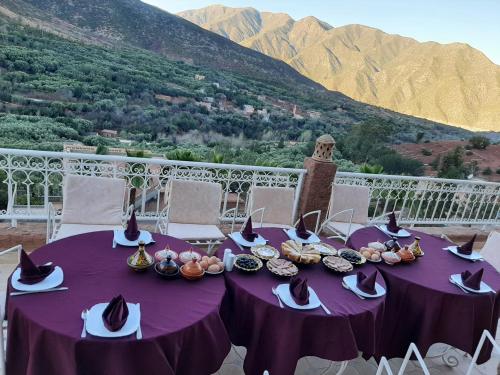 a purple table with food on it with mountains in the background at KASBAH LA DAME BIJA in Tassa Ouirgane