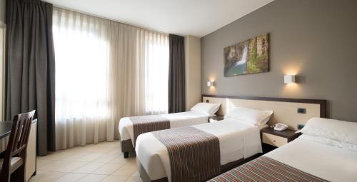 a hotel room with two beds and a window at Hotel Spinelli in Viareggio