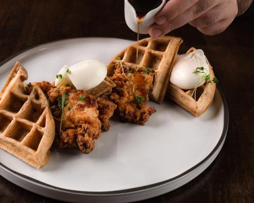 a plate with waffles and fried chicken and eggs at Century Plaza Hotel in Vancouver