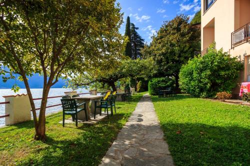 a walkway with chairs and a table next to the water at Miralago Casa in Menaggio