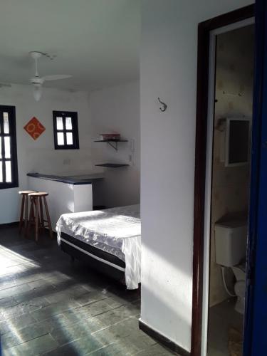 a bedroom with a bed and a table and windows at Santorini Flats in Arraial do Cabo