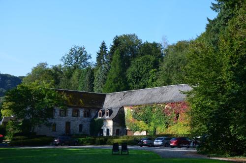 an old building with cars parked in a parking lot at Hotel Le Moulin Des Ramiers in Crupet