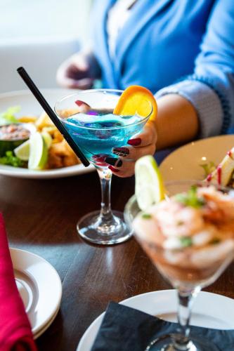 a person holding a drink on a table with plates of food at Hotel 11, MOD A Sonesta Collection in Calgary