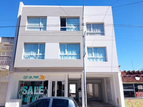 um edifício branco com um sinal de venda em frente em Departamentos Apart PM em Necochea