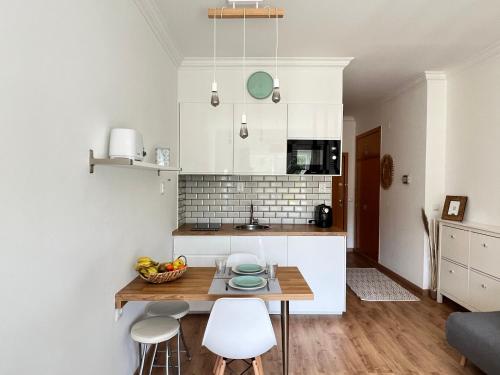 eine Küche mit einem Tisch und 2 weißen Stühlen in der Unterkunft Seaven Ericeira Beach Studio in Ericeira