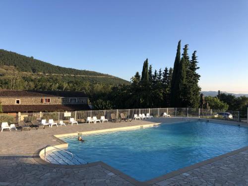 a swimming pool with chairs and a person in the water at Ludocamping in Lussas