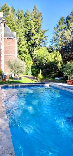 une grande piscine bleue devant une maison dans l'établissement Domaine de la Croix de Saint Lambert, à Poix-Terron