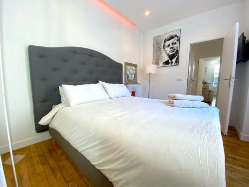 une chambre avec un grand lit blanc avec une grande tête de lit dans l'établissement L'appartement Passy, à Paris