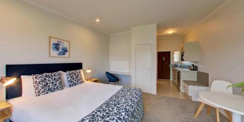 a bedroom with a large bed and a kitchen at Alpine Lake Motel in Taupo