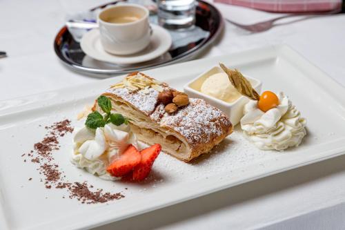 a white plate with a piece of cake and whipped cream at Restaurant Gästehaus Wiesenheim in Uderns