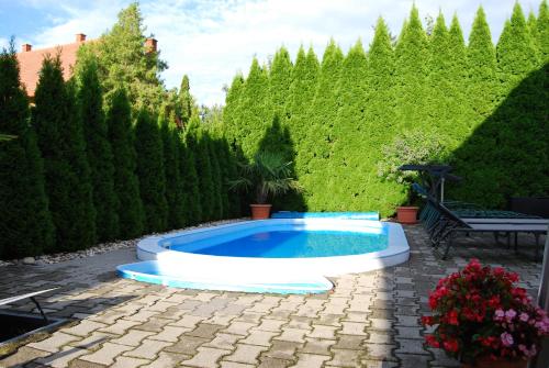 a swimming pool in a yard with trees and bushes at Barackvirág Vendégház in Tihany