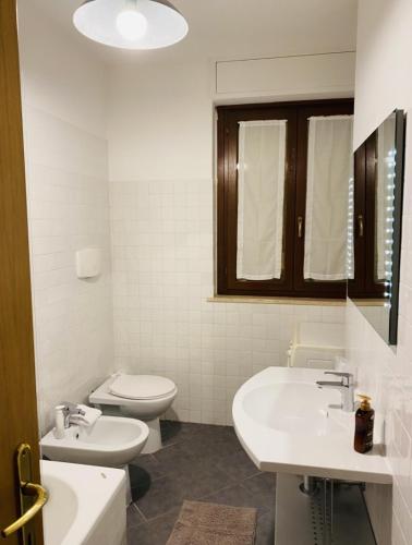 a white bathroom with two sinks and a toilet at Silio 12 in Foligno
