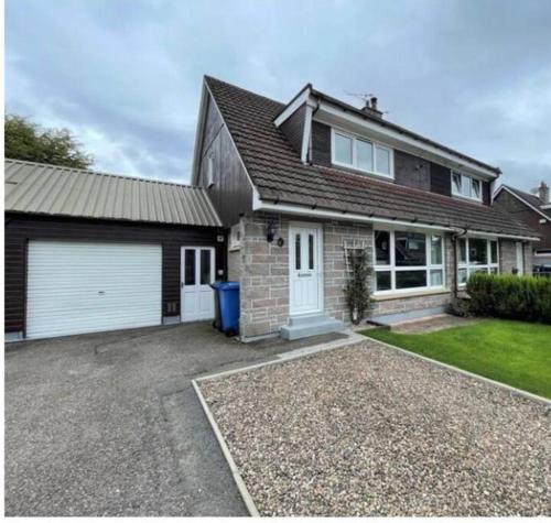 a brick house with a garage and a driveway at Delightful, central 3 bedroom house with garden & free parking in Inverness