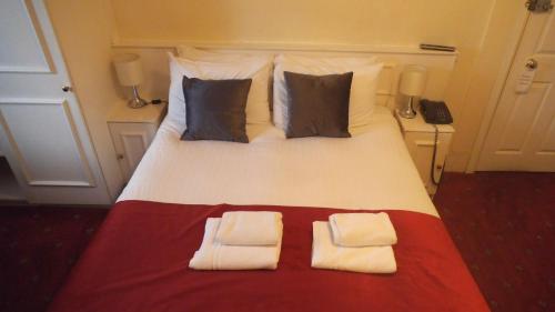 una camera da letto con un grande letto con due cuscini di Arran House Hotel a Londra