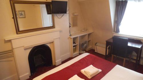 a bedroom with a fireplace and a bed and a mirror at Arran House Hotel in London
