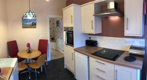una cocina con armarios blancos y una mesa pequeña y una cocina con comedor. en White Acre, en Scarborough