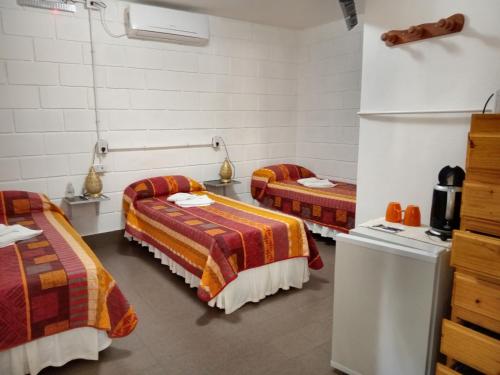 a room with two beds and a refrigerator at Hostería El Peregrino in Villa Cura Brochero