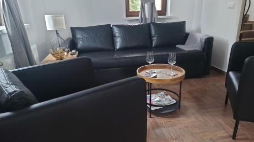 uma sala de estar com um sofá preto e uma mesa com copos de vinho em Mazurskie Siedlisko Langen em Mrągowo