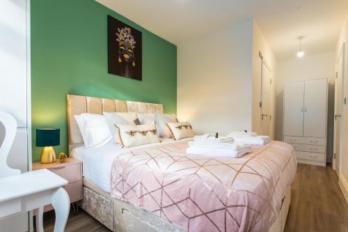 a bedroom with a large bed and a green wall at Hatfield Haven - Modern 2-Bed Retreat near Uni, Business Park & City Center, FREE Parking, Big savings on Longer Stays in Hatfield