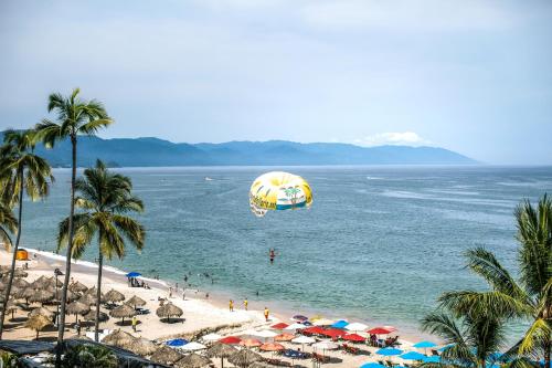 a beach with umbrellas and a balloon flying over the ocean at El Dorado 404 in Puerto Vallarta
