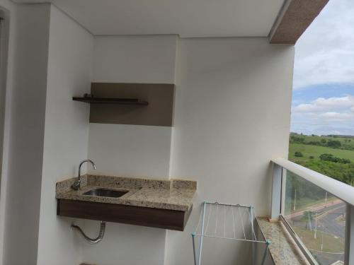 une cuisine avec un évier mural à côté d'une fenêtre dans l'établissement Apartamento em Olímpia, à Olímpia