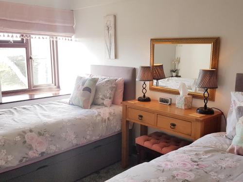 a bedroom with two beds and a mirror at Wethercote Cottage in Cold Kirby