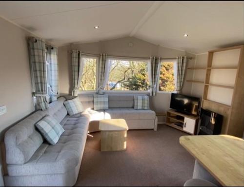 a living room with a couch and a tv at Emma's Escape accessible caravan at Durdle Door in West Lulworth