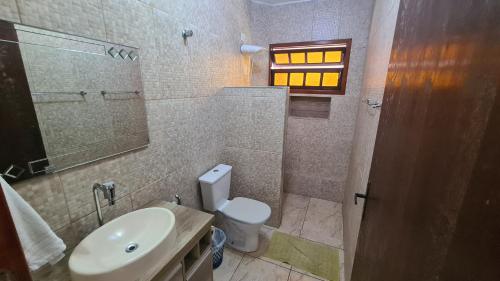 a bathroom with a sink and a toilet and a window at Pousada Retiro das Caravelas in Cananéia